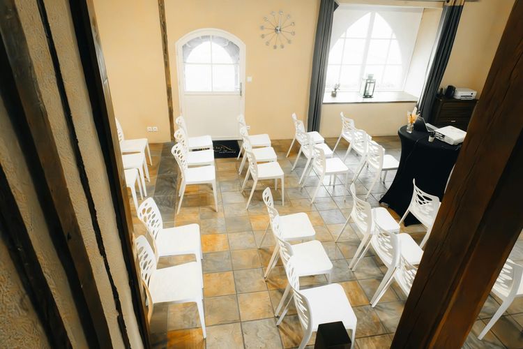 Bright meeting room setup with white chairs and large windows for natural light.