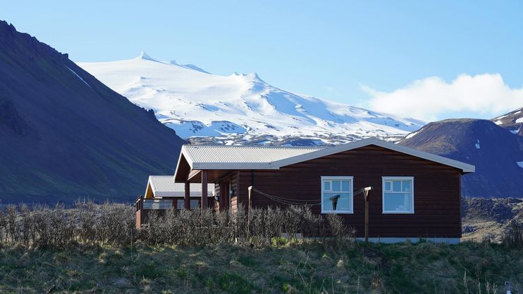 Cozy wooden cabin set against the dramatic Icelandic mountains and glaciers.