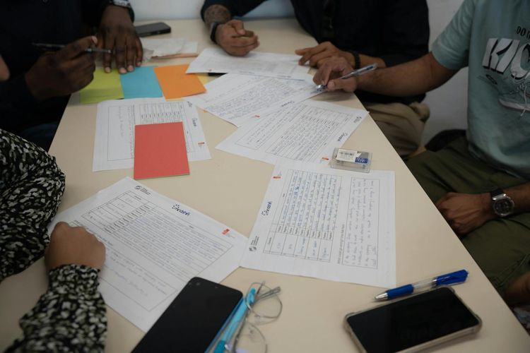 A diverse team working together, reviewing documents and making notes during a collaborative meeting.