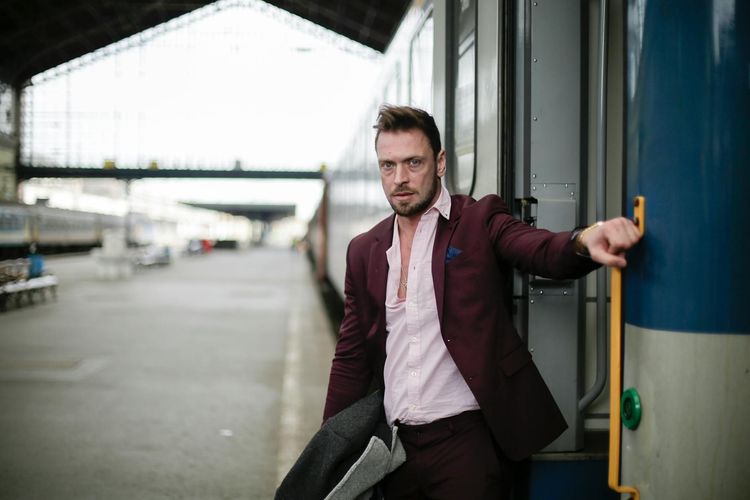 A man in smart attire boarding a train at a bustling station, capturing travel and urban life.