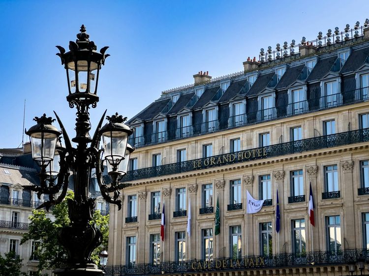 Historic Le Grand Hotel in Paris with classic architecture and Parisian street lamp.