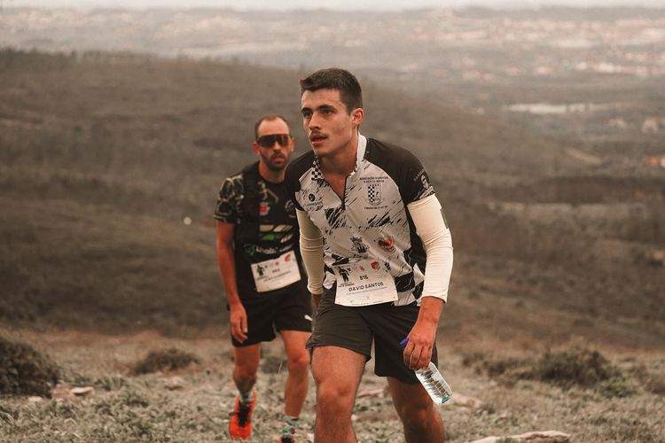 Two determined trail runners climbing a hillside during a marathon, showcasing endurance and scenic landscape.