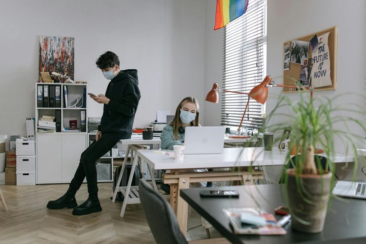 Two masked individuals working in a contemporary office setting, embracing the new normal.