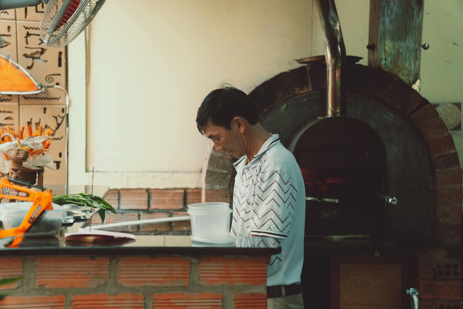A chef working near a traditional oven in a Vietnamese restaurant kitchen in Dalat. A chef working near a traditional oven in a Vietnamese restaurant kitchen in Dalat.
