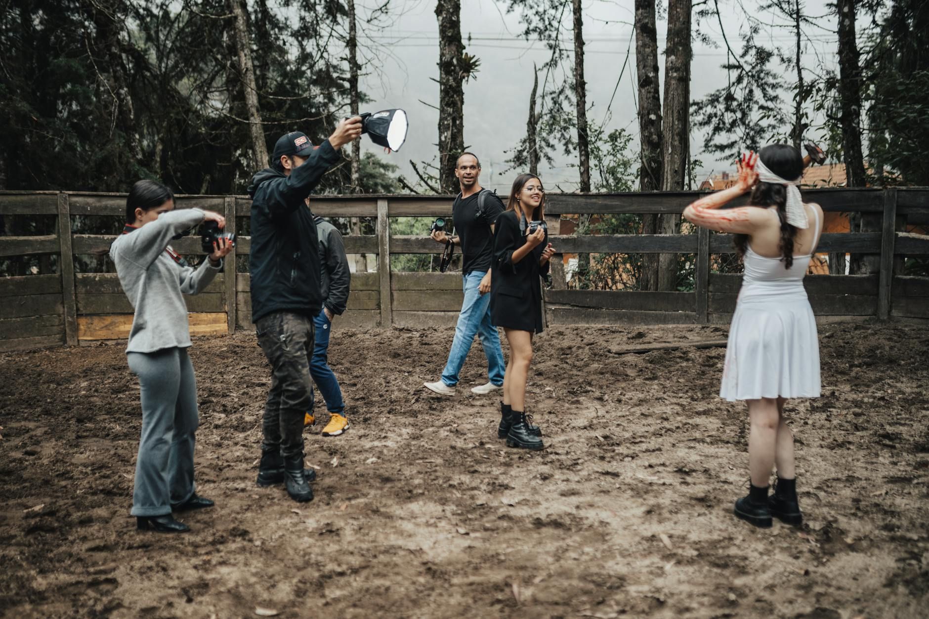 A group of photographers conducts an outdoor fashion photoshoot with a model in a white dress.