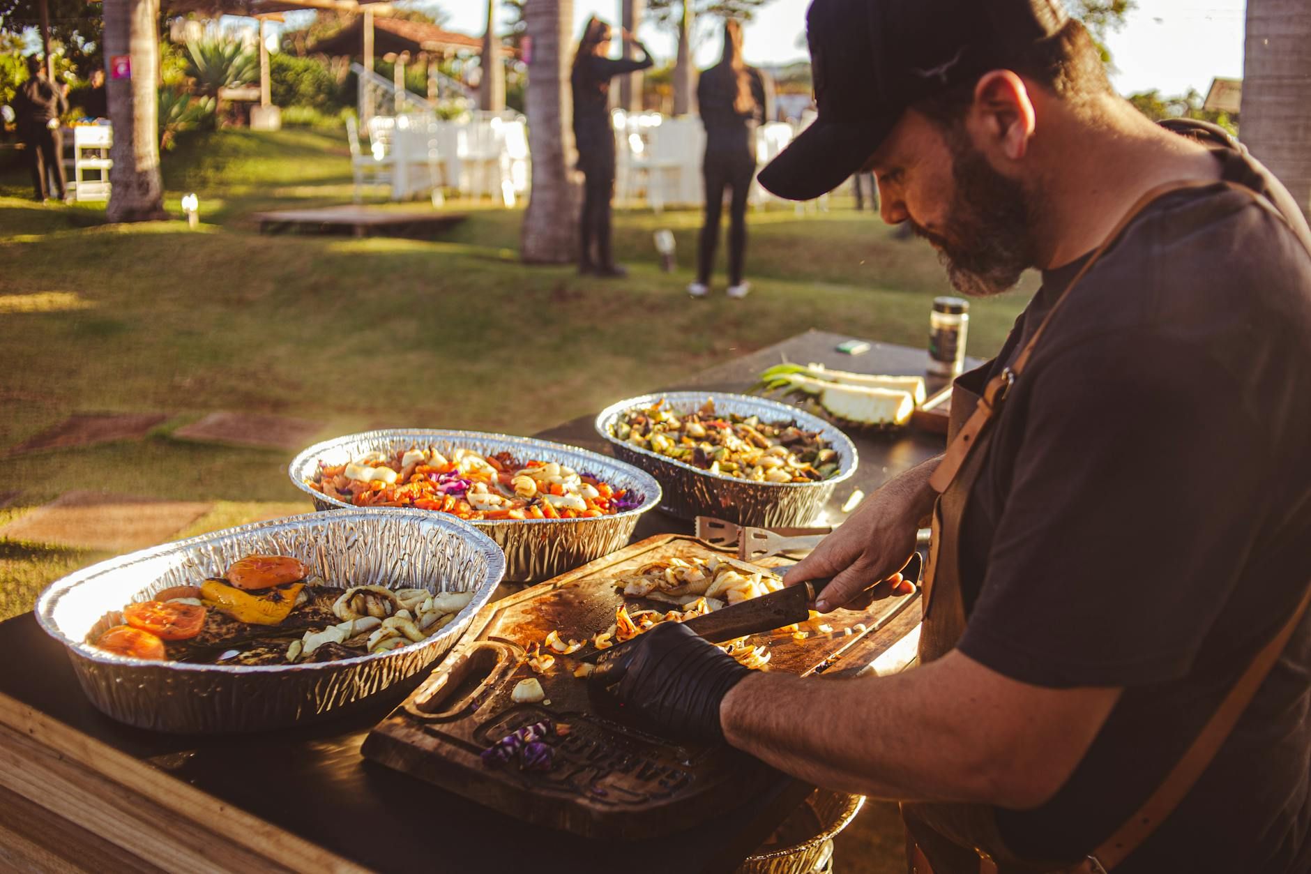 Chef preparing grilled vegetables at an outdoor event with natural lighting and festive atmosphere. Chef preparing grilled vegetables at an outdoor event with natural lighting and festive atmosphere.