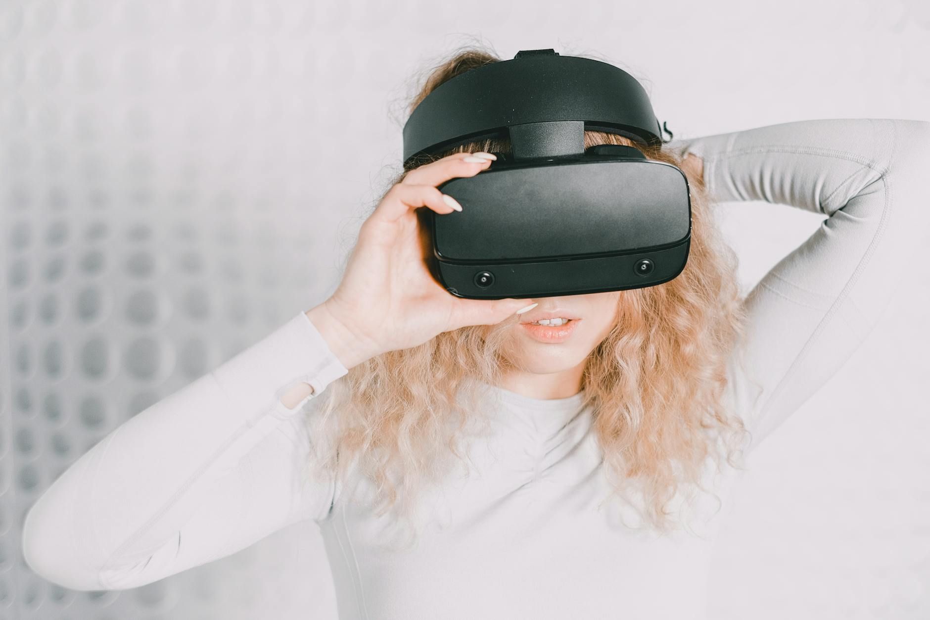 Blonde woman using a VR headset exploring virtual reality indoors. Blonde woman using a VR headset exploring virtual reality indoors.