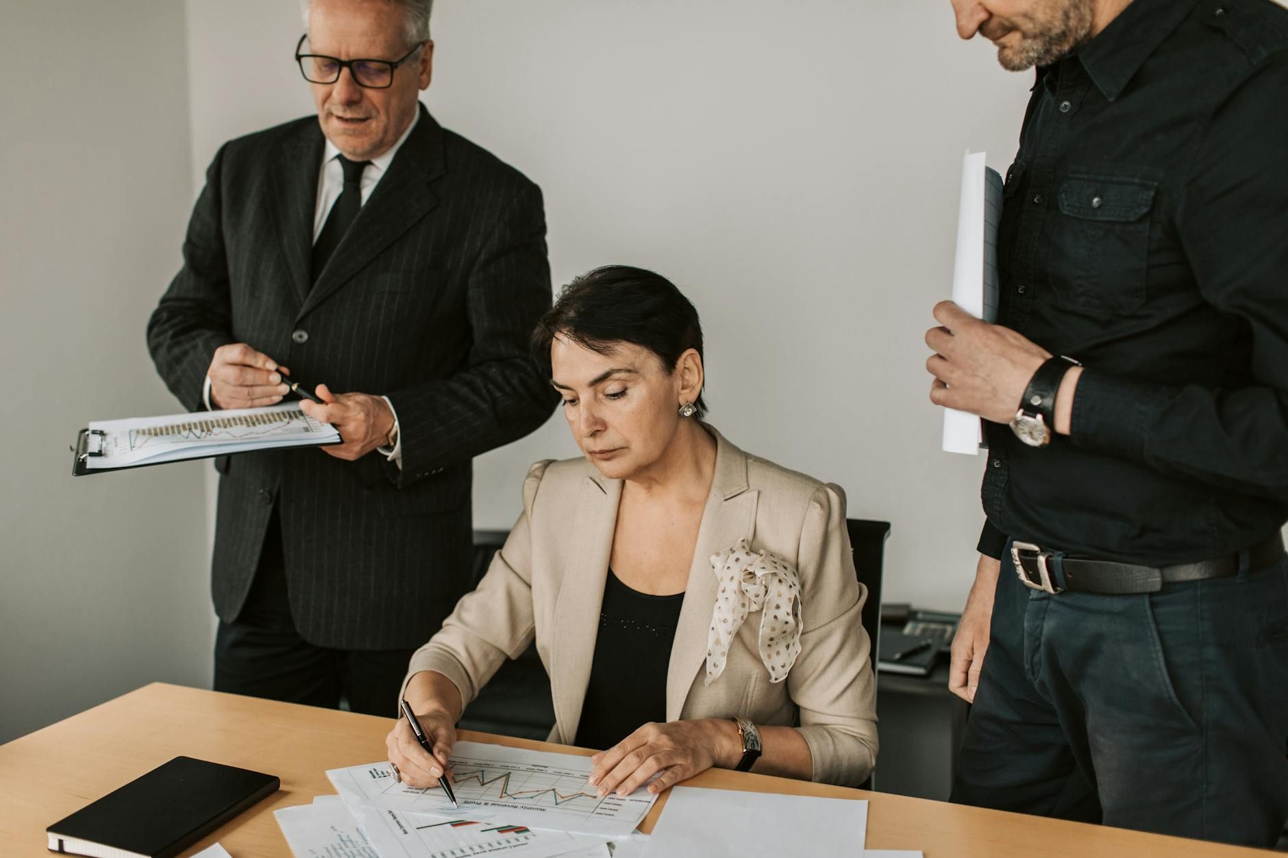 Business professionals collaborating on financial documents in an office setting. Business professionals collaborating on financial documents in an office setting.