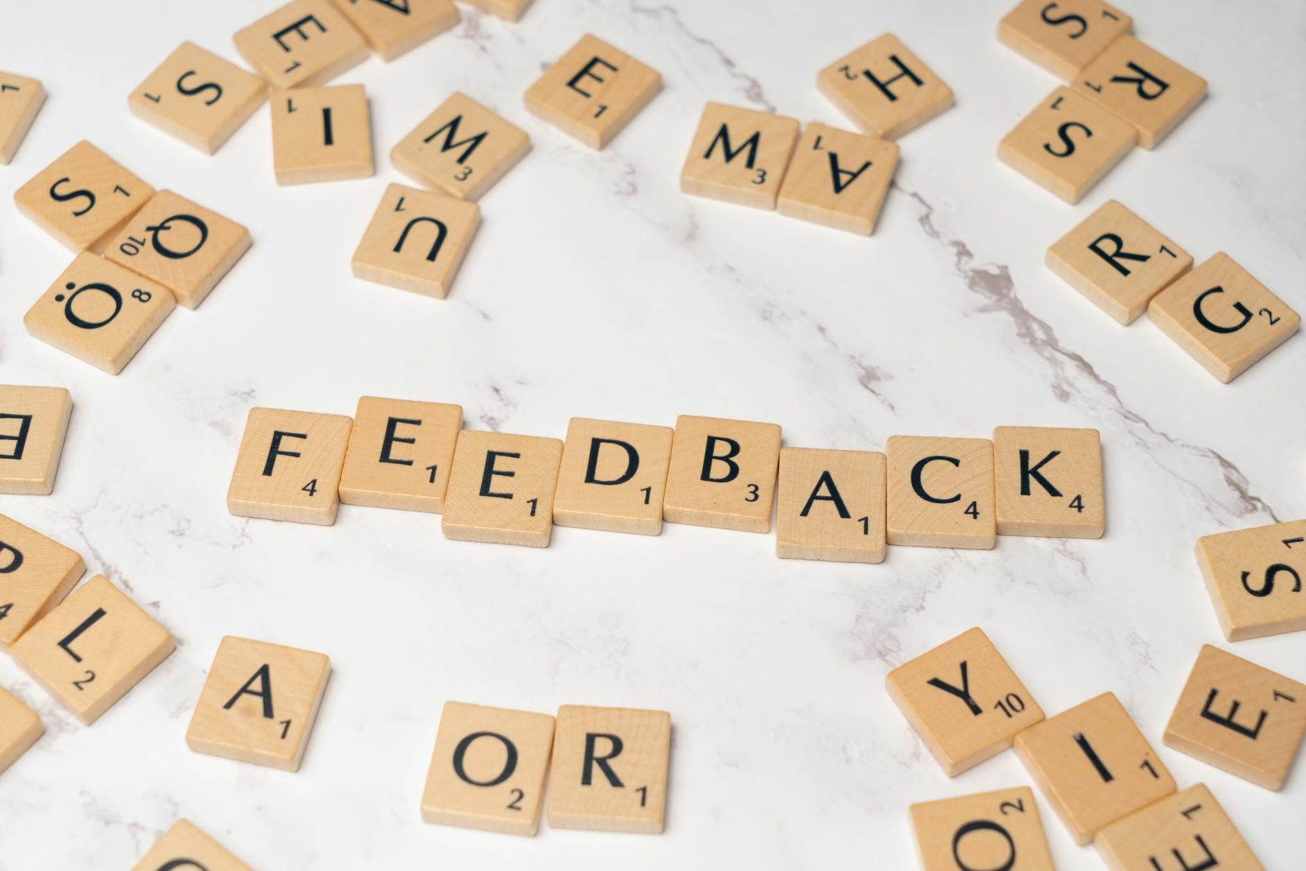 Wooden Scrabble tiles arranged to spell 'Feedback' on a marble background. Wooden Scrabble tiles arranged to spell 'Feedback' on a marble background.