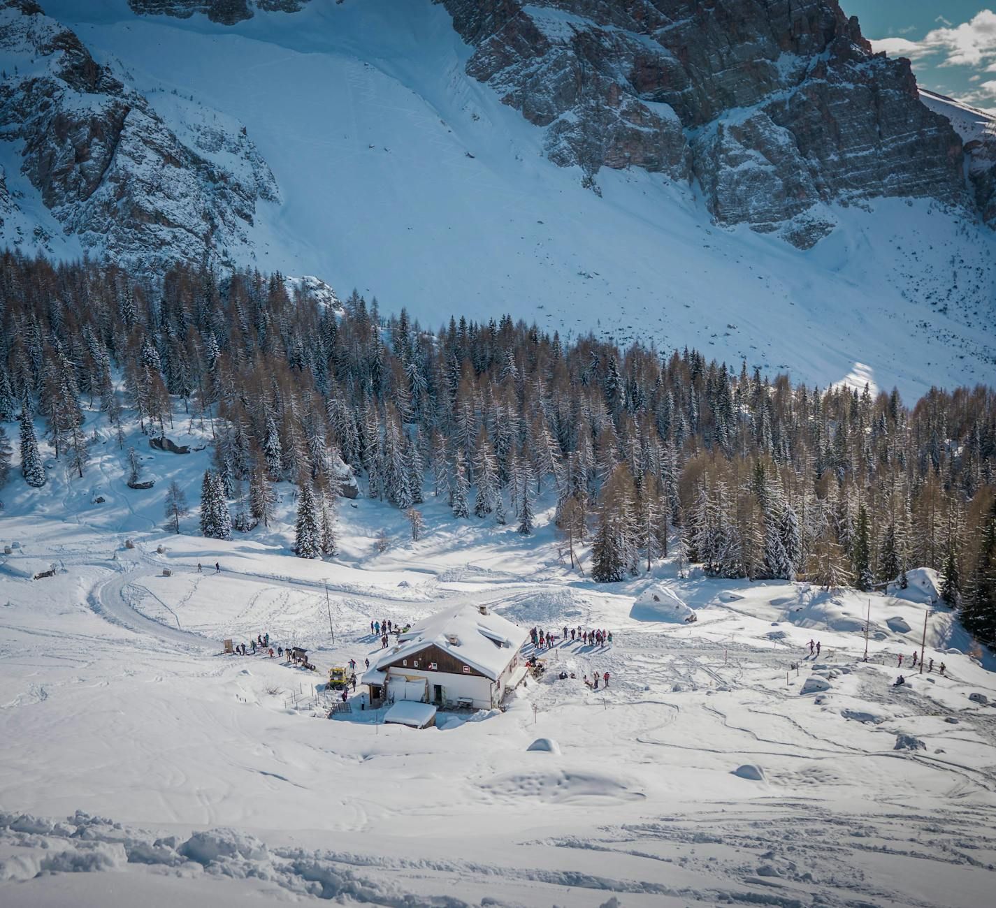 Una pintoresca cabaña de montaña nevada en un bosque invernal, rodeada de majestuosos picos. Una pintoresca cabaña de montaña nevada en un bosque invernal, rodeada de majestuosos picos.
