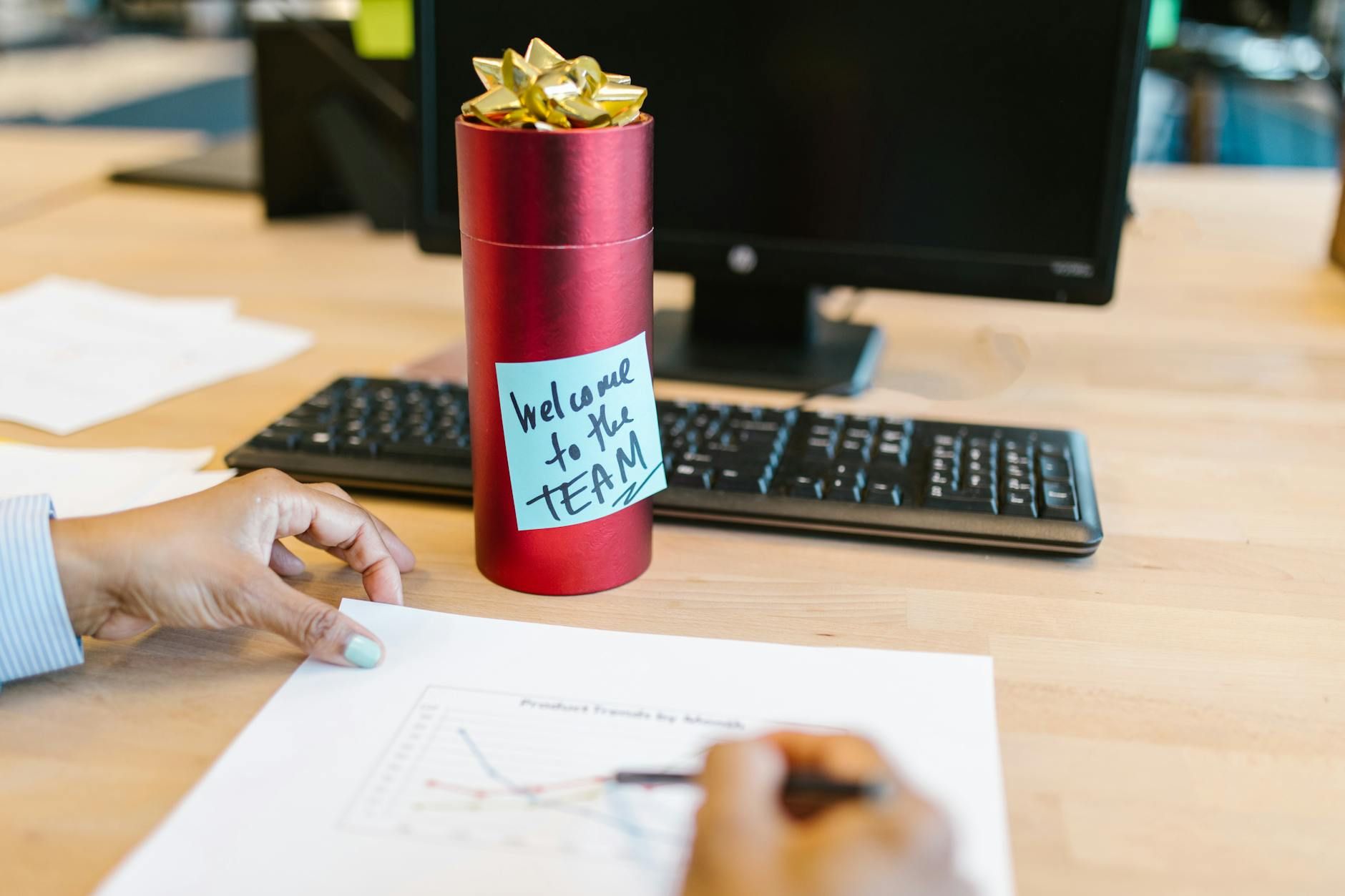 A welcoming gift on an office desk with a computer and person holding a chart. A welcoming gift on an office desk with a computer and person holding a chart.