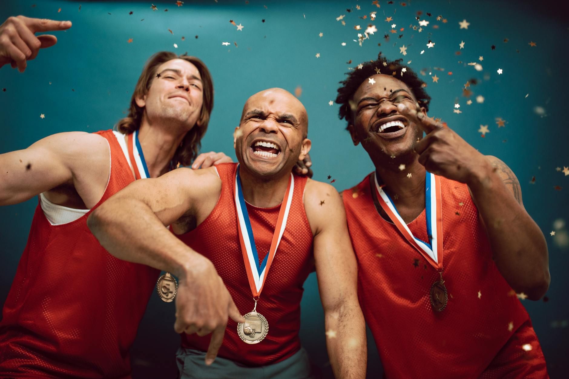 Three diverse athletes celebrate their victory with medals and confetti. Three diverse athletes celebrate their victory with medals and confetti.
